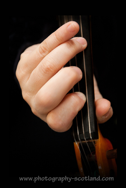 Photo - view from above of a hand on the neck of a fiddle