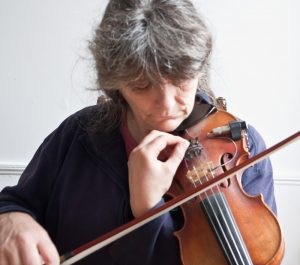 Holding the fiddle to tune it by ear